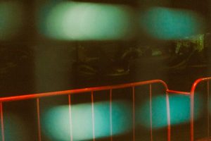 Red metal barrier or guardrail with glowing cyan light and dark abstract background
