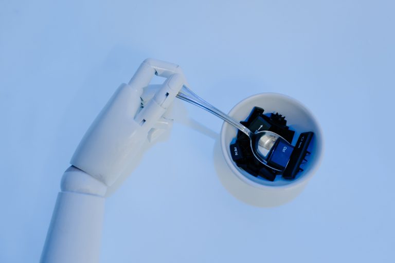 A robotic hand holds a spoon filled with keyboard keys, symbolizing AI and technology fusion