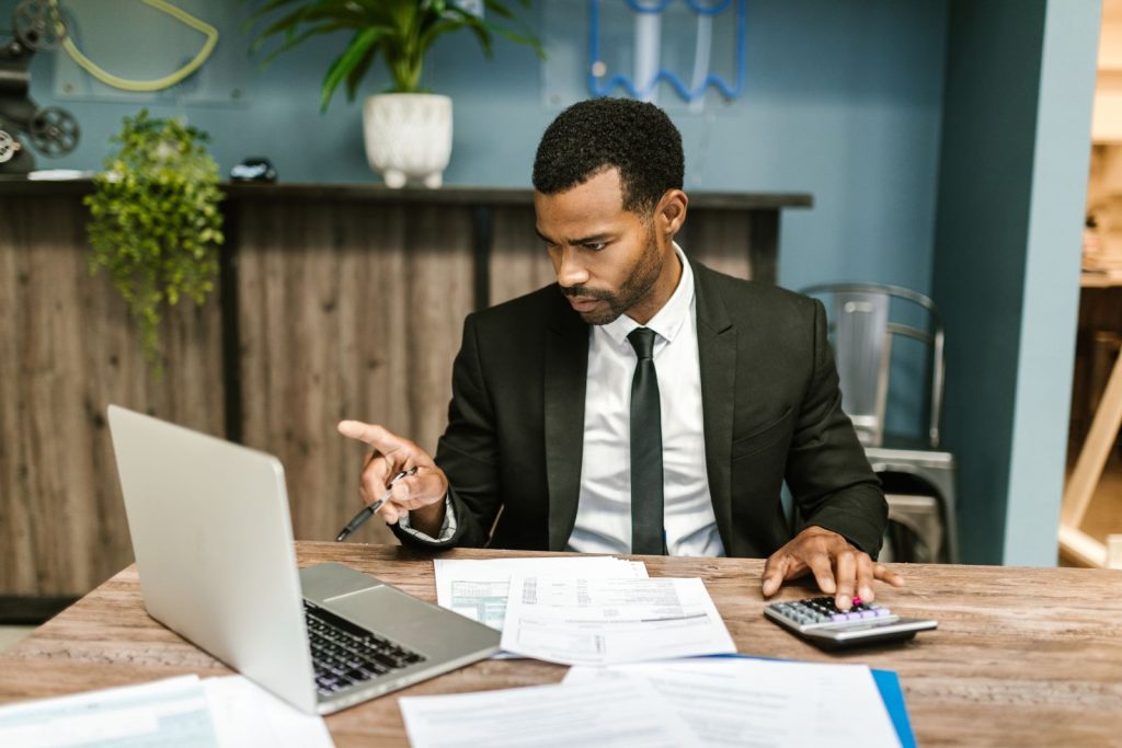 An investor reviews financial documents beside a laptop and calculator