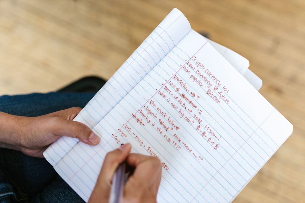 A person writing cryptocurrency notes in a notebook, highlighting Bitcoin and future predictions