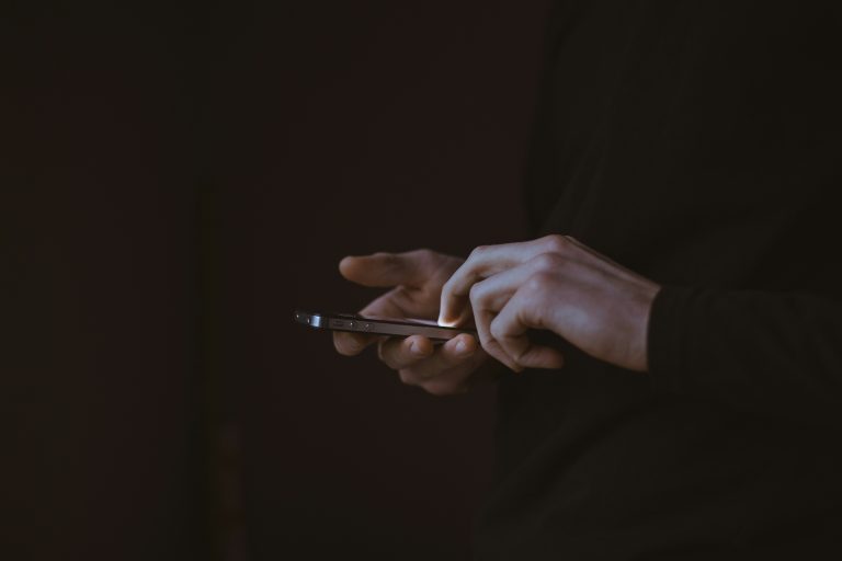 Hands using a smartphone in a dark setting